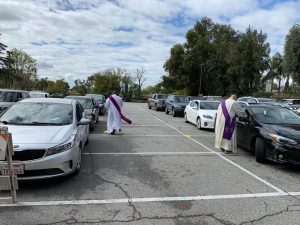 Deacons distribute holy Communion to parishioners in their cars. 