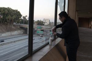 Fr. Raymont Medina, priest secretary to Archbishop Gomez, lights a candle in support of medical workers and their families along the edge of the Cathedral of Our Lady of the Angels plaza overlooking the 101 freeway in downtown Los Angeles. (Sarah Yaklic)