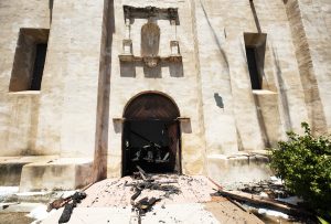 Charred rubble spills out of the church doors. (Victor Alemán/Angelus News)