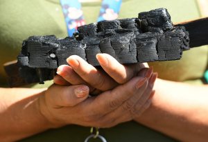 A parishioner holds charred wood from the fire-damaged San Gabriel Mission. (Photo by John McCoy)