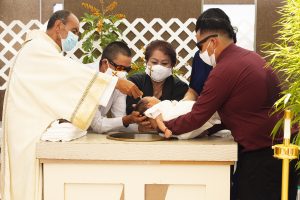An infant is baptized outdoors at Our Lady Queen of Angels Church, or “La Placita,” near downtown LA Aug. 1. (Victor Alemán)
