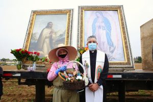 Father Ochoa poses with a farmworker in front of the images. (David Amador Rivera/Angelus News)