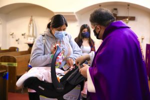 Fr. Domingos Machado, O.A.R., gives a baby ashes at Cristo Rey Church in Atwater Village Feb. 17. (David Amador Rivera) 