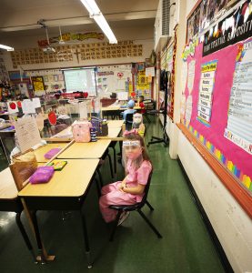 Kindergarteners sit at a distance, behind Plexiglass barriers, on Feb. 1, at Resurrection School in Boyle Heights. They were invited to dress as essential workers for the first day of Catholic Schools Week. (Victor Alemán)