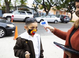 A Resurrection School student gets his temperature checked before heading into the building for class. (Victor Alemán)