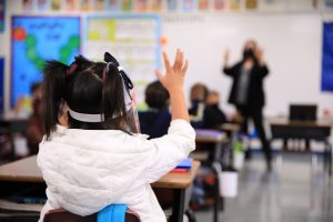 A kindergartener raises her hand in class at St. Bernard School (David Amador Rivera)