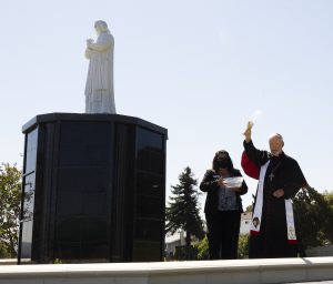 Bishop David O'Connell blesses a statue of St. John Vianney, patron saint of priests, in the new burial section at Queen of Heaven Cemetery. (Victor Alemán)