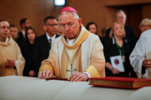 Archbishop Gomez lays a crucifix on Bishop David O'Connell's casket at his funeral Mass March 3, 2023. (Robert St. John/LA Times)