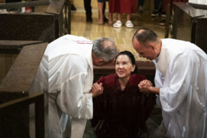 One of the nine adult catechumens welcomed into the Catholic Church at the cathedral this Easter emerges from the baptismal pool during the Easter Vigil. (Victor Alemán)