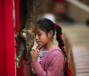 A young girl venerates at the foot of the cross during the celebration of the passion of the Lord on Good Friday.  (Victor Alemán)