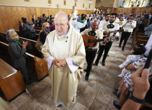 Msgr. John Moretta, pastor of Resurrection Church in Boyle Heights, walks out with mariachi performers following a special Mass on April 30 celebrating 55 years since his ordination to the priesthood and 40 years at Resurrection. (Victor Alemán)