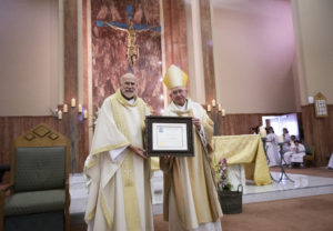 Archbishop José H. Gomez awards a special certificate to Our Lady of Refuge's pastor Fr. Gerard O'Brien during the parish’s 75th anniversary Mass on May 14. (Victor Alemán)