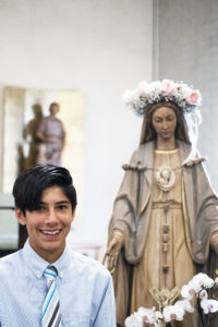 Liam Kasper, a seventh-grader at St. Dorothy School in Glendora, poses with the crowned Blessed Virgin Mary during a May 5 May Crowning Mass. (Victor Alemán)