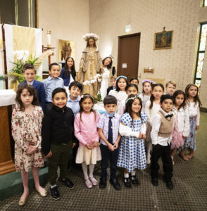 First-graders at St. Dorothy School in Glendora gather around a statue of the Blessed Virgin Mary adorned with a crown of flowers following a May 5 May Crowning Mass, one of several celebrated in Catholic schools around the archdiocese in May. (Victor Alemán)