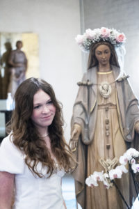Radley Wray, a seventh-grader at St. Dorothy School in Glendora, poses with the crowned Blessed Virgin Mary during a May 5 May Crowning Mass. (Victor Alemán)
