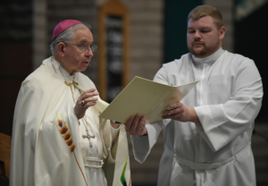 Seminarian Stephen Watson assists Archbishop José H. Gomez at a prayer vigil at St. Paschal Baylon Church in Thousand Oaks for victims of the Borderline shooting in 2018. Watson will be ordained a transitional deacon May 27. (John McCoy)