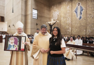 Liliana Espinoza, a 7th grader at St. Gregory the Great School in Whittier, was recognized at the Oct. 17 Missionary Childhood Association Mass as a national finalist in last year’s MCA Christmas Artwork Contest. She was presented with a framed print of her artwork by Msgr. Terrance Fleming, executive director of the LA archdiocese’s Mission Office, and Auxiliary Bishop Matthew Elshoff, who celebrated the Mass. The original art piece will be on display at the National Shrine of the Immaculate Conception in Washington D.C. during Advent 2023. (Victor Alemán)