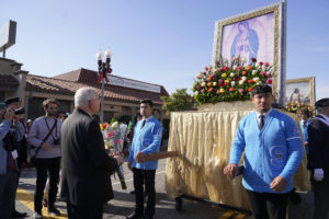 Los Angeles Archbishop José H. Gomez places flowers at the base of the pilgrim image during the 92nd Procession and Mass honoring Our Lady of Guadalupe and St. Juan Diego at East LA College Stadium on Dec. 3. (Sarah Yaklic)
