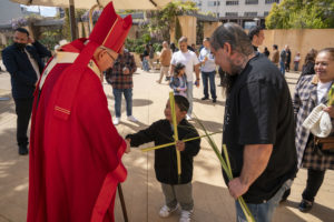 Archbishop José H. Gomez greets a young boy following the Palm Sunday Mass on March 24. (John Rueda)