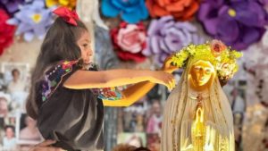 A young lady crowns the Mary statue during a May Crowning event at Our Lady of Grace Church in Encino. (Napoleon Ibarra)