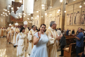 Cynthia Sosa waves as she and her newly ordained husband, Renee, walk out after the permanent deacon ordination Mass on June 8. (Victor Alemán)