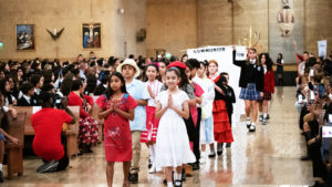 Students process in holding signs to begin the annual Missionary Childhood Association Youth Appreciation Mass on Oct. 16. (Victor Alemán) 