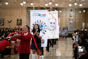 Students process in holding signs to begin the annual Missionary Childhood Association Youth Appreciation Mass on Oct. 16. (Victor Alemán) 