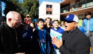 Los Angeles Archbishop José H. Gomez, left, laughs along with Father Rodel Balagtas, right, pastor at Incarnation Church, and students during an event at Incarnation School in Glendale on Nov. 8 to celebrate funds raised for Catholic Education Foundation of Los Angeles thanks to the Dodgers winning the World Series. (Victor Alemán)