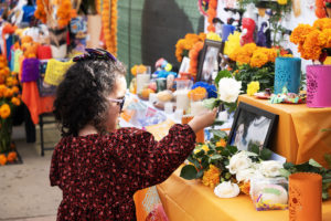 A young girl adds a white rose to one of the dozens of altars set up at San Fernando Mission Cemetery on Nov. 2. (Victor Alemán)