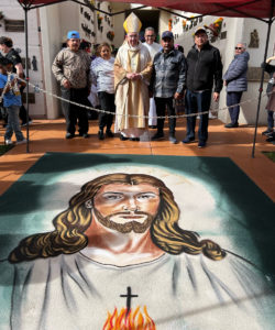 Archbishop José H. Gomez with attendees behind a sawdust carpet, or alfombra, depicting the Sacred Heart of Jesus at a Día de los Muertos celebration at Santa Clara Cemetery in Oxnard on Nov. 2. (Maria Hurtado)