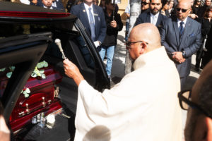 Father Jim Anguiano sprinkles holy water over the casket of Dodgers legend Fernando Valenzuela following his funeral Mass on Nov. 6 at the Cathedral of Our Lady of the Angels. (Victor Alemán)