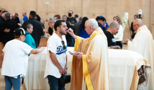 Los Angeles Archbishop José H. Gomez offers Communion to a Dodgers fan during Fernando Valenzuela's funeral Mass on Nov. 6 at the Cathedral of Our Lady of the Angels. (Victor Alemán)