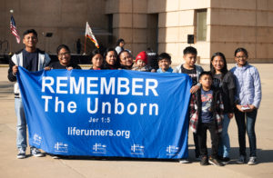 Attendees hold up a Life Runners pro-life banner during OneLife LA at the Cathedral of Our Lady of the Angels on Jan. 18. (Victor Alemán)