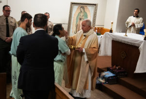 Archbishop José H. Gomez offers Communion during Mass for inmates at LA Men's Central Jail during his annual visit on Christmas Day. (Victor Alemán)