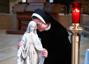 A religious sister embraces the Virgin Mary statue that survived  the Eaton Fire during the OneLife LA celebration at the Cathedral of Our Lady of the Angels on Jan. 18. (Victor Alemán)