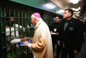 Archbishop José H. Gomez shakes hands and blesses inmates at LA Men's Central Jail during his annual visit on Christmas Day. At right is LA County Sheriff Robert Luna. (Victor Alemán)