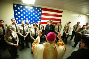 Archbishop José H. Gomez blesses LA County Sheriff Robert Luna and other sheriff's deputies at LA Men's Central Jail during his annual visit and Mass on Christmas Day. (Victor Alemán)