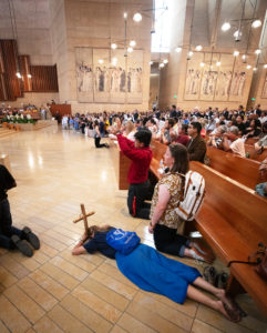 A woman prostrates herself and others kneel during Eucharistic adoration for the feast of Corpus Christi at the Cathedral of Our Lady of the Angels on June 22 during the National Eucharistic Pilgrimage. (Victor Alemán)