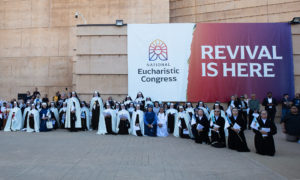 Attendees of the Corpus Christi Mass at the Cathedral of Our Lady of the Angels on June 22 stand in the outdoor plaza under a banner for the National Eucharistic Revival. (Victor Alemán)