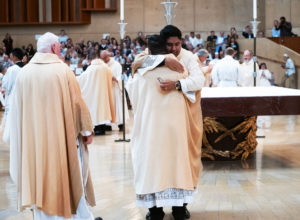 Father Jorge Moncada receives an embrace after being vested with his stole and chasuble during the ordination Mass on May 31. (Victor Alemán)