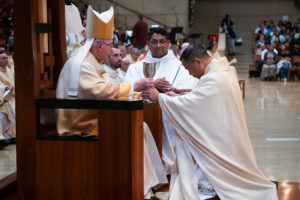 Archbishop José H. Gomez hands over the bread and wine to newly ordained Father Allan Carodan during the ordination Mass at the Cathedral of Our Lady of the Angels on May 31. (Victor Alemán)