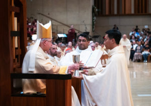 Archbishop José H. Gomez hands over the bread and wine to newly ordained Father Quoc Vo during the ordination Mass at the Cathedral of Our Lady of the Angels on May 31. (Victor Alemán)