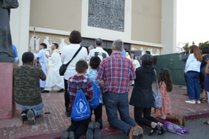 Pilgrims wearing Camino de California backpacks kneel during a Eucharistic procession at Mission San Gabriel Arcángel on June 21 as part of the National Eucharistic Pilgrimage. (Katie Trejo)
