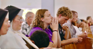Rachel Levy, center, and Stephen Fuhrmann, right, perpetual pilgrims with the National Eucharistic Pilgrimage, pray during a Mass at Mission San Gabriel Arcángel on June 21. (Reese Cuevas)