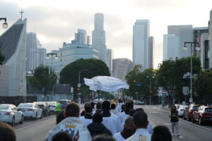 The downtown LA skyline is visible while hundreds walk behind the Blessed Sacrament during a Eucharistic procession through Skid Row in Los Angeles on July 19. (Alex Salcedo)