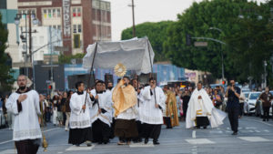 A priest carries the Blessed Sacrament while hundreds follow behind during a Eucharistic procession through Skid Row in downtown Los Angeles on July 19. (Alex Salcedo)
