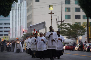 A priest carries the Blessed Sacrament at dusk while hundreds follow behind during a Eucharistic procession through Skid Row in downtown Los Angeles on July 19. (Alex Salcedo)