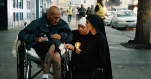 Women religious sisters engage with a man in a wheelchair during a Eucharistic procession through Skid Row in downtown Los Angeles on July 19. (Archdiocese of Los Angeles)