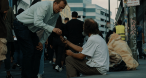 A man in the procession hands a homeless man a rosary during a Eucharistic procession through Skid Row in downtown Los Angeles on July 19. (Archdiocese of Los Angeles)