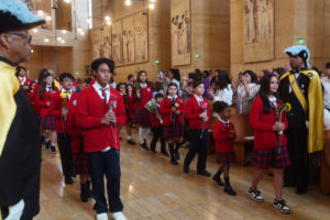 Catholic school students carry flowers to place in front of the Virgin Mary statue during the “One Mother, Many Peoples” Mass at the Cathedral of Our Lady of the Angels on Sept. 6, which celebrated the diverse cultures, organizations, and ethnic ministries in the Archdiocese of Los Angeles. (Reese Cuevas/Archdiocese of Los Angeles)